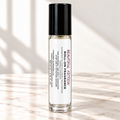 Beautiful Fiction 10 mL roll-on fragrance with full warning label on ivory marble and white background