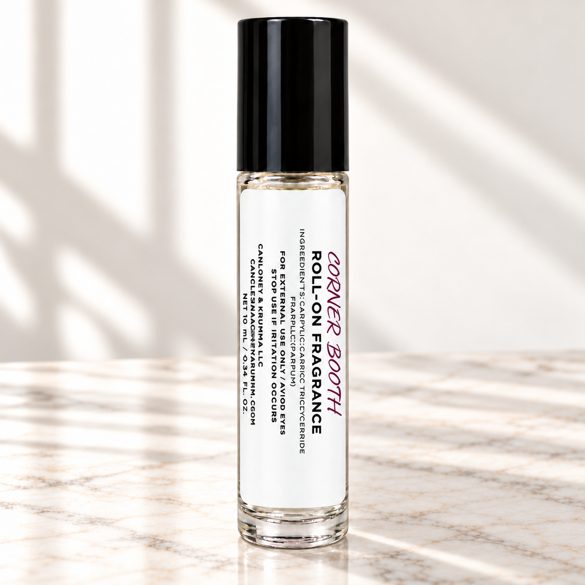 Corner Booth 10 mL roll-on fragrance with full warning label on ivory marble and white background