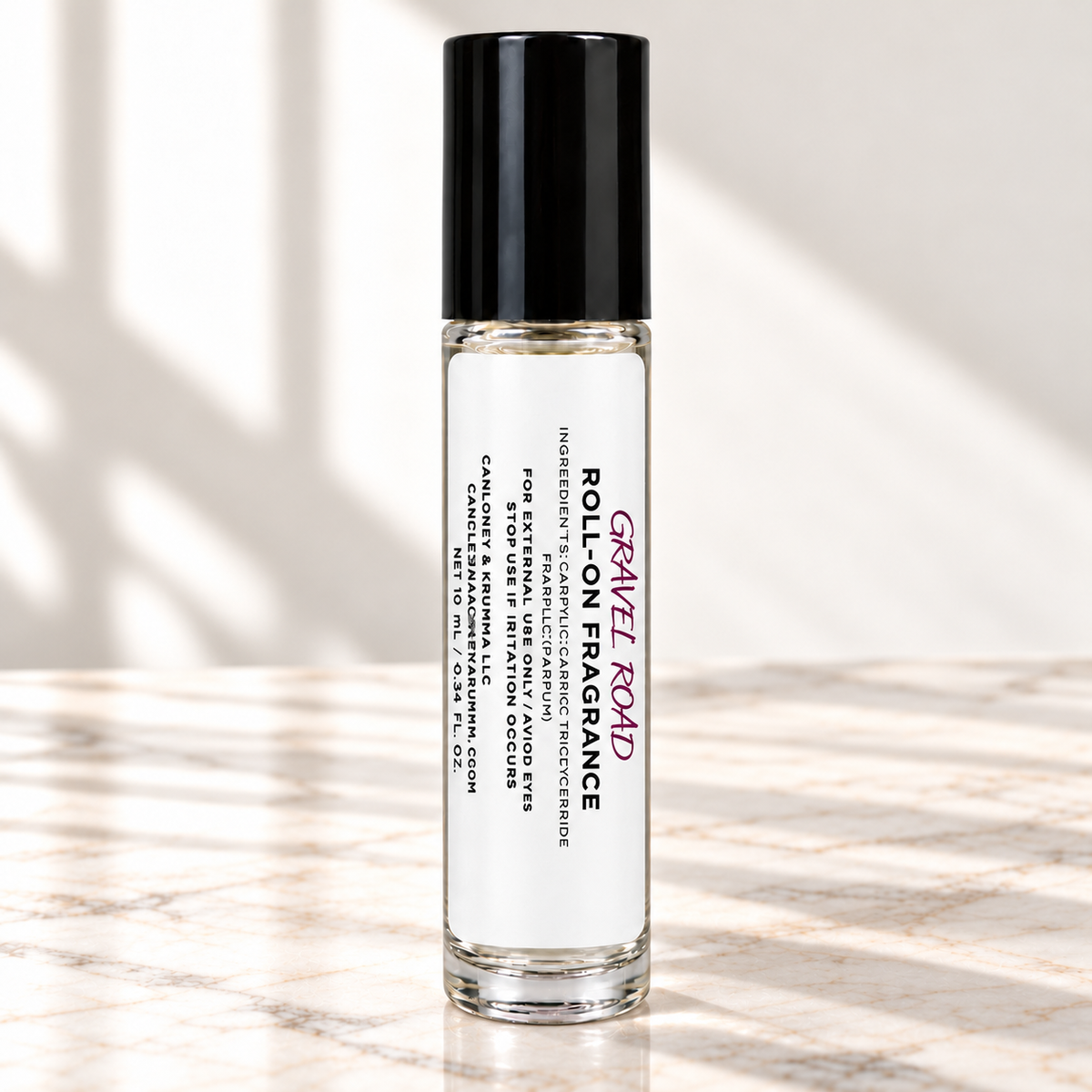 Gravel Road 10 mL roll-on fragrance with full warning label on ivory marble and white background