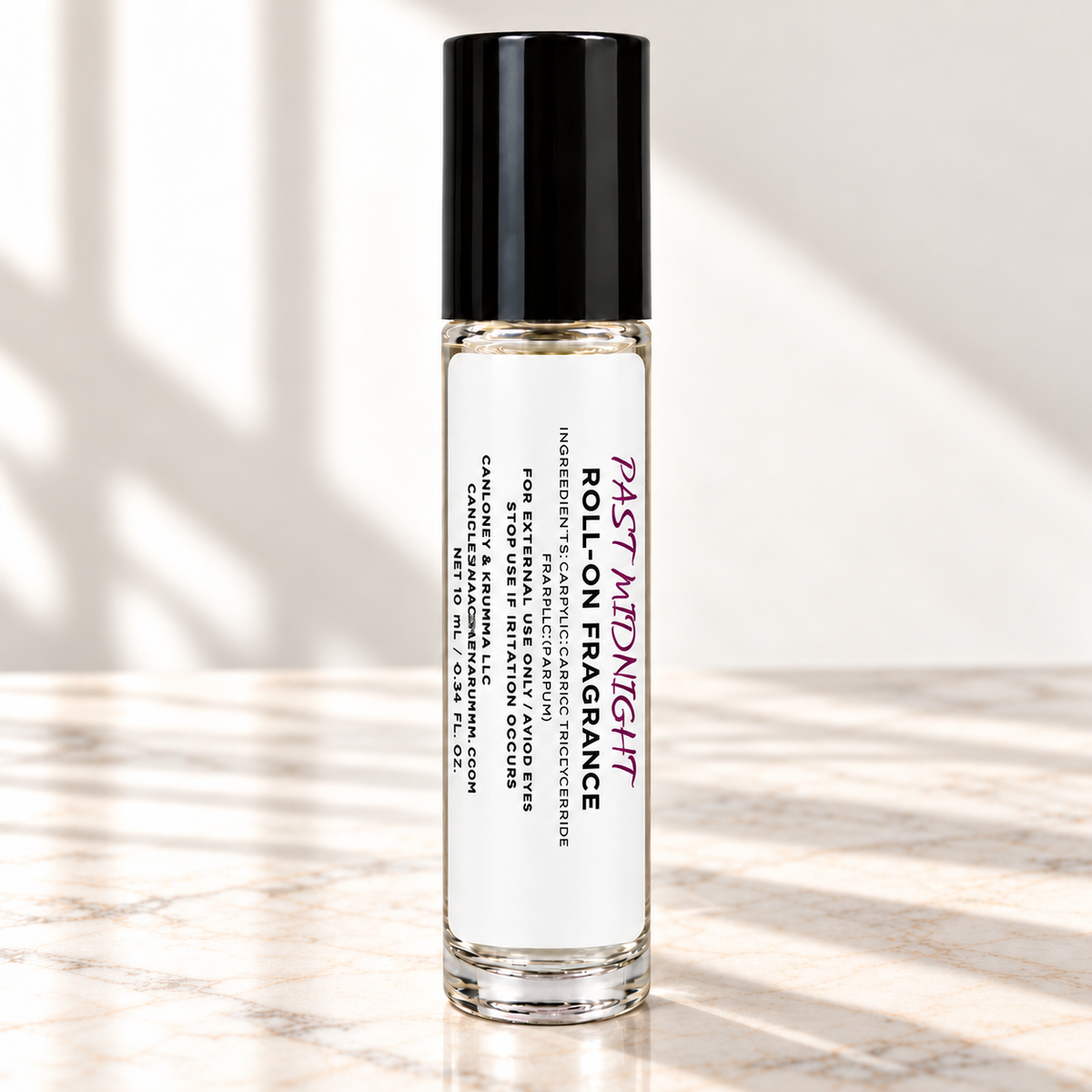 Past Midnight 10 mL roll-on fragrance with full warning label on ivory marble and white background