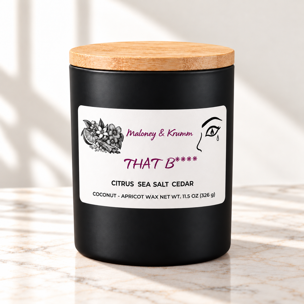 That B**** candle in matte black jar on ivory marble with white background
